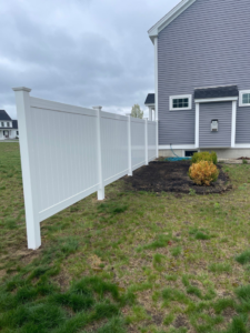 A clean white privacy vinyl fence installed in a side yard by Vinyl Fences Inc. in Dover, NH.