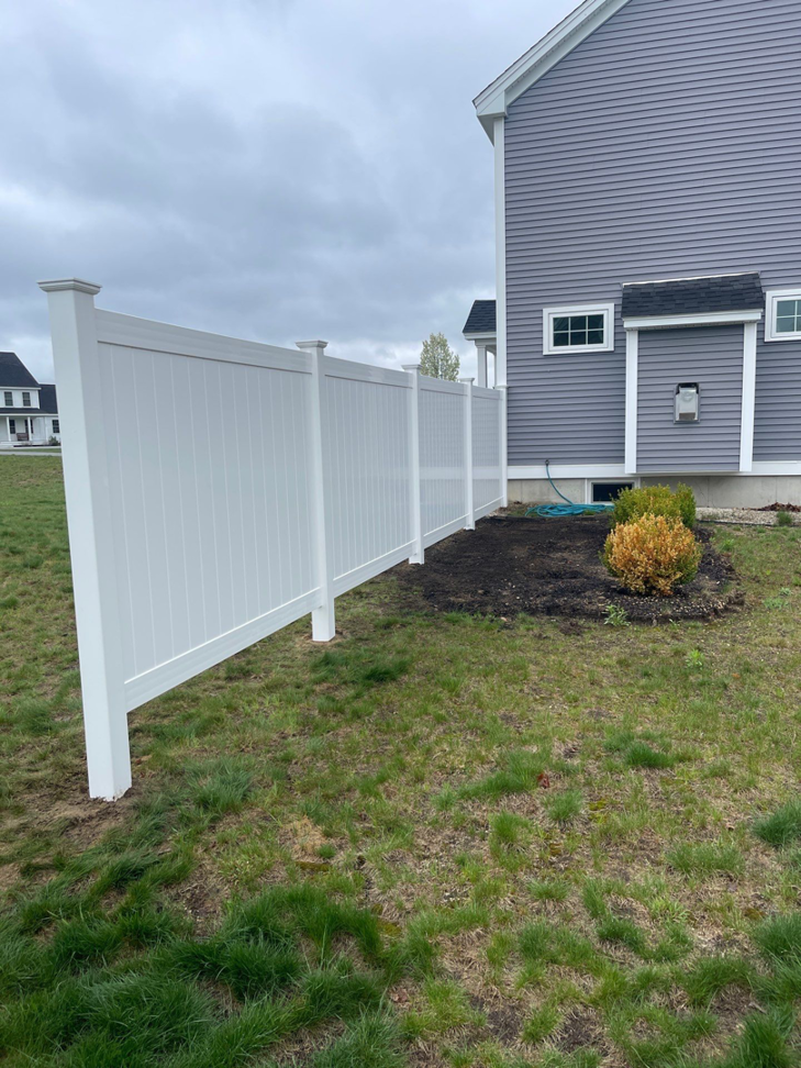 A clean white privacy vinyl fence installed in a side yard by Vinyl Fences Inc. in Dover, NH.