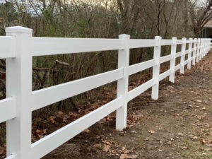 A classic white rail fence bordering a wooded area, installed by Stand Strong Fencing of Plano, TX