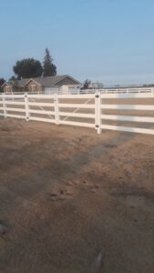 A white ranch-style fence with a gate on a rural property by Angel Fencing Inc. in Fresno, CA