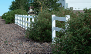 A white ranch-style fence installed by Fence Tech in Everett, WA, bordering a natural landscape.