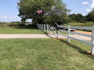 A white ranch-style fence with an automatic gate installed by ProScape Outdoor Construction LLC in Norman, OK.