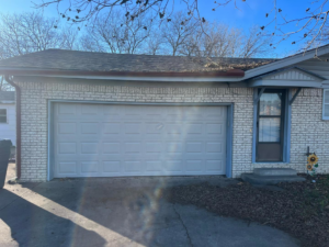 A white residential garage door on a brick house, installed by Hometown Garage Doors in Crestview, FL.