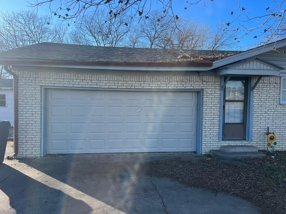 A white residential garage door on a brick house, installed by Hometown Garage Doors in Crestview, FL.