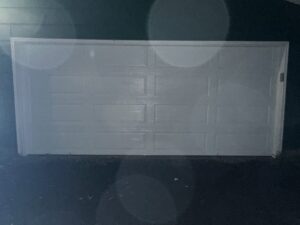A white residential garage door illuminated at night by AJK Door Services in Duluth, MN.