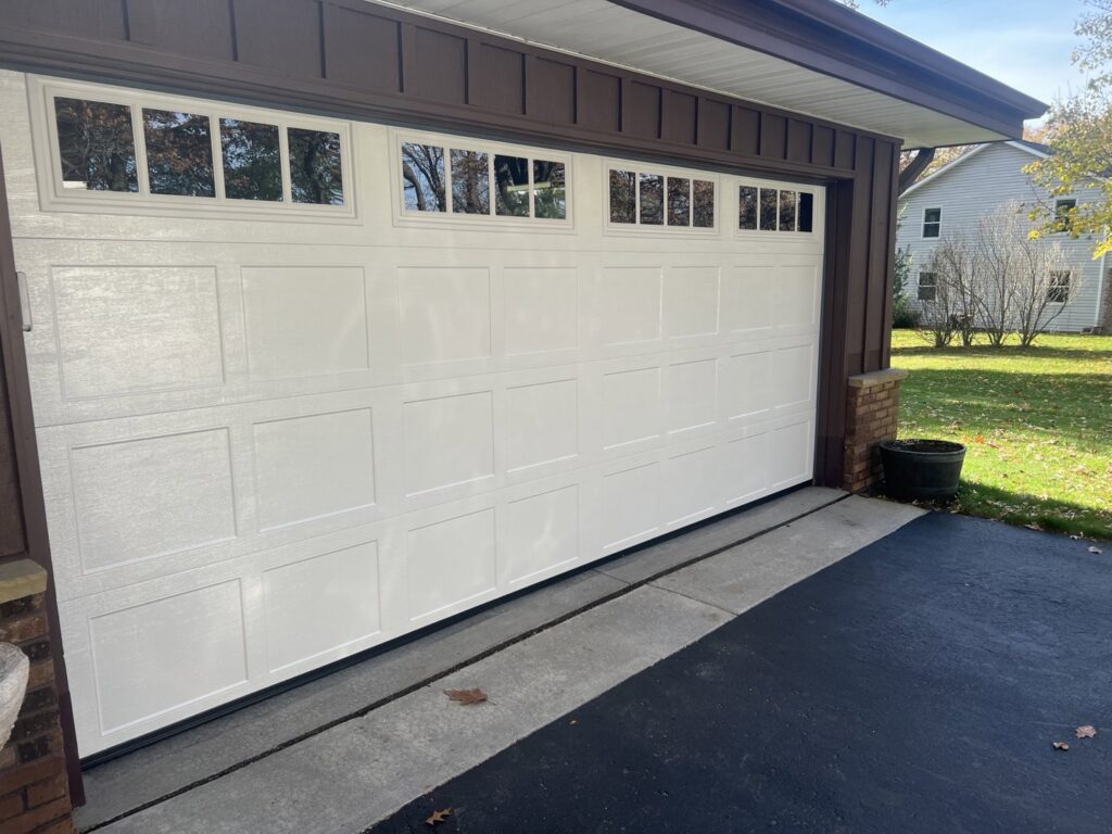 A newly installed white residential garage door with decorative top windows by McDonald Overhead Door Inc. in Kenosha, WI.