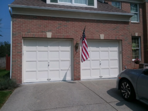 Two white residential garage doors on a brick house, installed by Midland Glass and Garage Doors in Frederick, MD