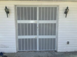 White security double doors with a mesh pattern installed by Ability Burglar Bars in Jacksonville, FL.