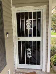 White security screen door with decorative scrollwork installed by Ability Burglar Bars in Jacksonville, FL.