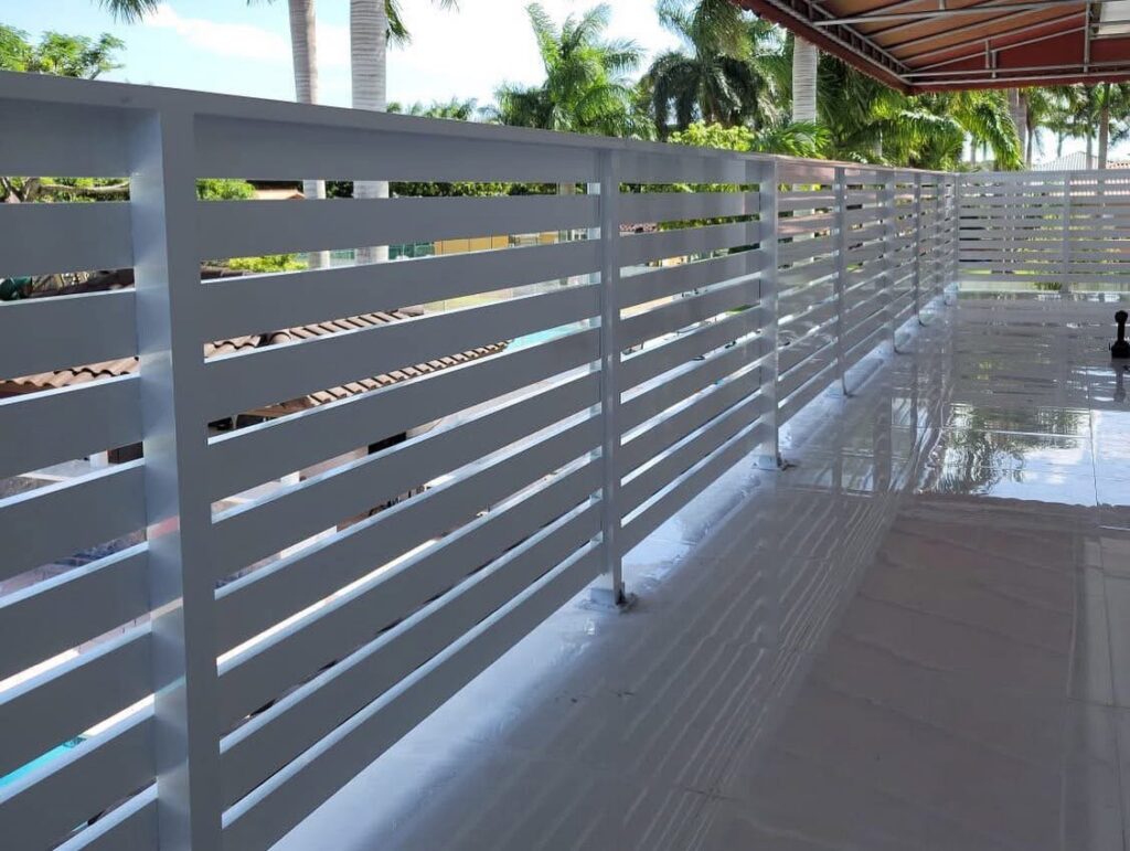 A white slatted balcony railing providing privacy and safety by Osuna Ornamental Fences & Gates in Cutler Bay, FL.