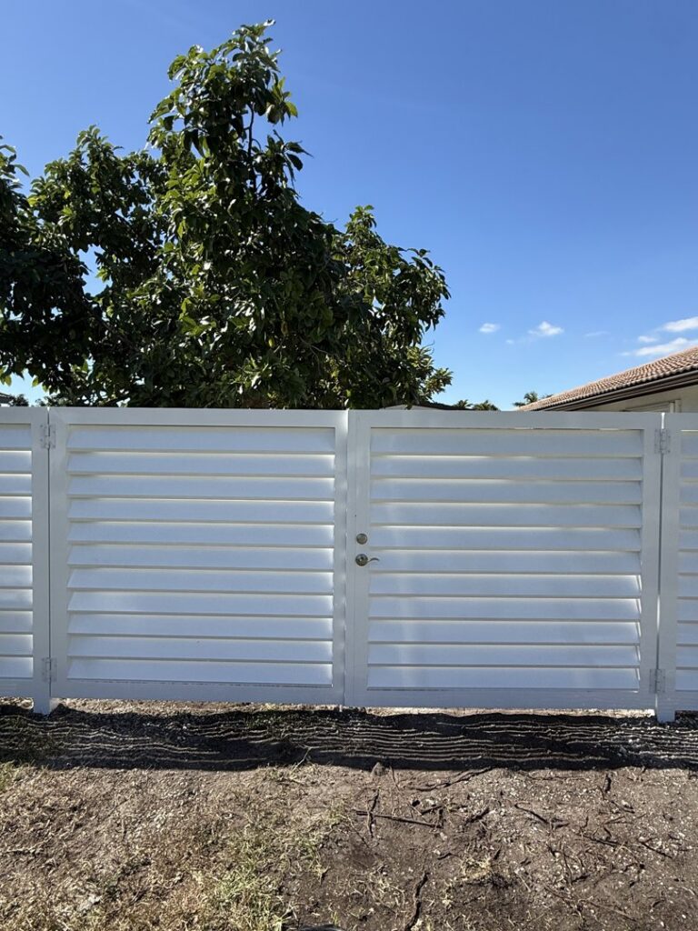 A newly installed white slatted privacy fence and gate by Osuna Ornamental Fences & Gates in Cutler Bay, FL.