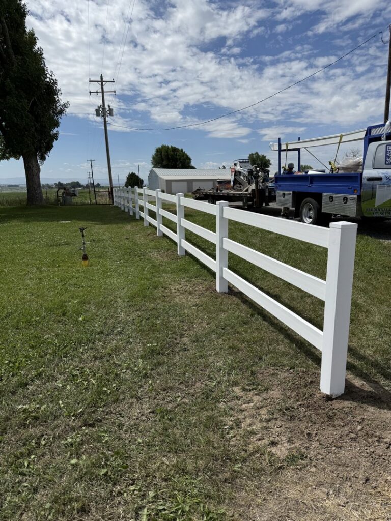 A new white split-rail style fence installed in a grassy field by All Over Fence Idaho in Jerome, ID