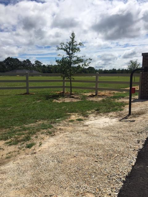A white three-rail farm-style fence with a gate entrance, installed by Custom Fence Builders in Gulfport, MS.