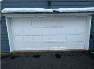 A white traditional residential garage door with snow on top, serviced by Hines Garage Doors Service & Repair in Seattle, WA.
