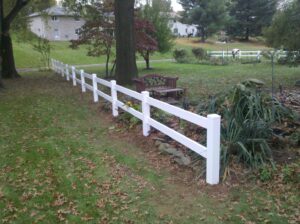 A white two-rail fence installed in a garden by Snyders Custom Fencing in York, PA.