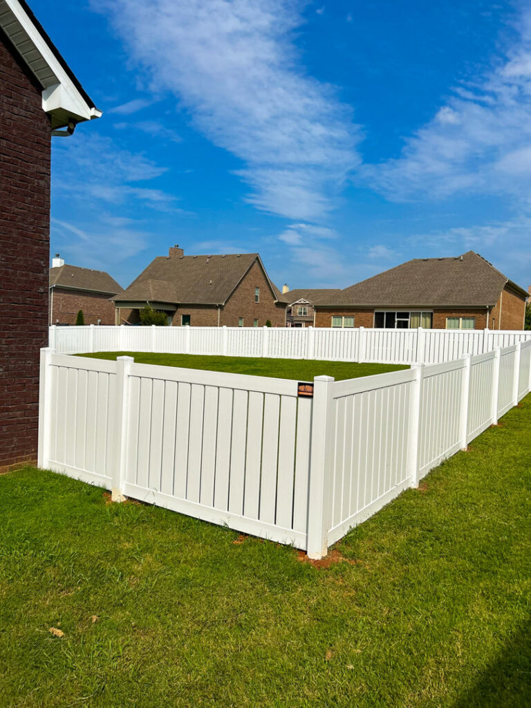 A corner section of a white vinyl privacy fence installed in a backyard by Pro Fence in Decatur, AL