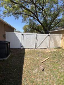 A white vinyl backyard fence with a double gate installed by Elite Fence and Outdoor of Tampa Bay in Tampa, FL.