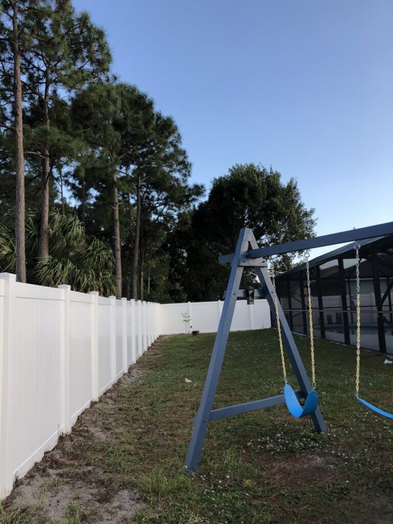 A durable white vinyl fence enclosing a backyard with a swing set, installed by Inovation Fence in Fort Worth, TX.