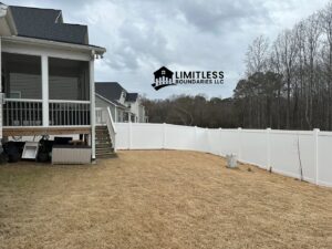 A newly installed white vinyl fence enclosing a backyard, adjacent to a screened porch, by Limitless Boundaries LLC in Garner, NC.