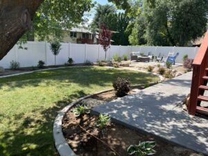 A pristine white vinyl privacy fence enclosing a landscaped backyard by Stonehenge Fence & Deck in Orem, UT.
