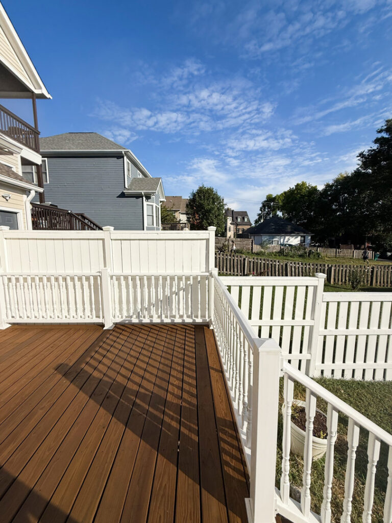 A white vinyl fence installed around a backyard deck by Heron Building Co in Franklin, TN.