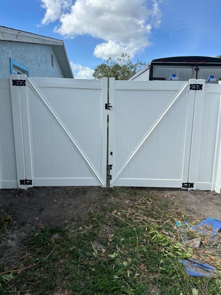 A newly installed white vinyl double gate with decorative black hardware by Santis Fence & Home Service in Tampa Heights, FL
