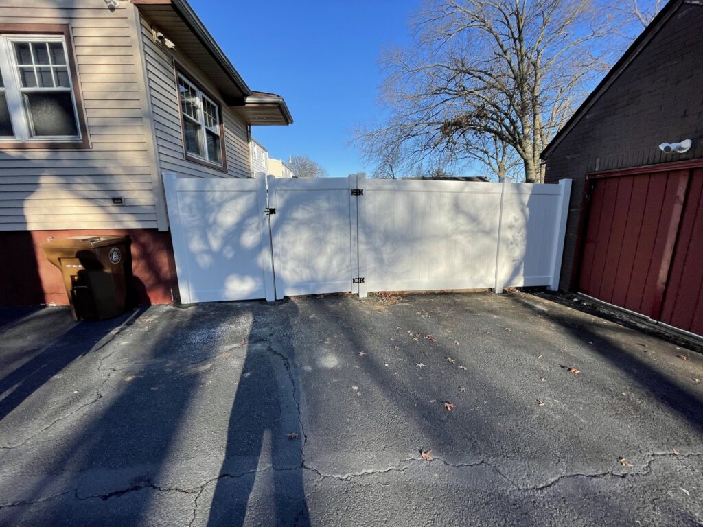 A white vinyl double gate installed across a residential driveway by Brothers Fence in Elizabeth, NJ.