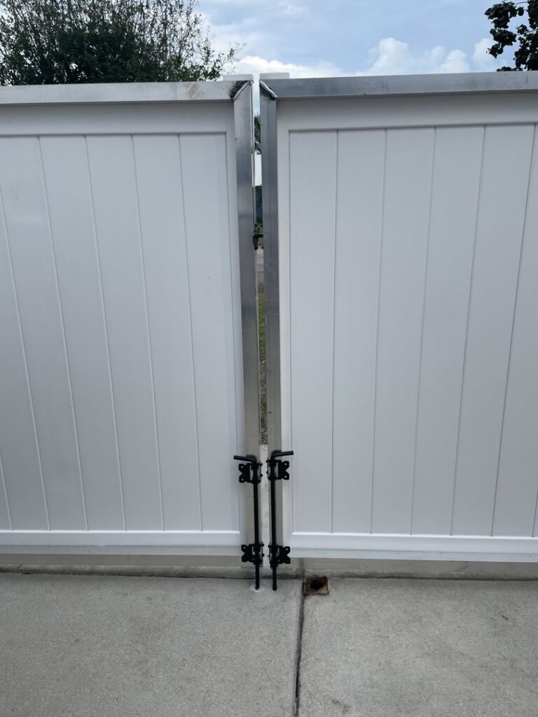 A sturdy white vinyl double gate with black latches, expertly installed by Inovation Fence in Fort Worth, TX.