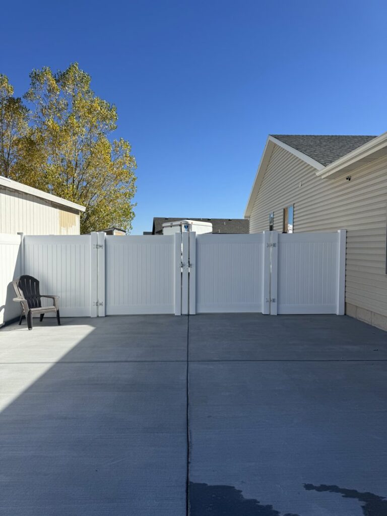 A white vinyl double gate installed on a concrete pad by 208 Fence and Gate in Idaho Falls, ID.