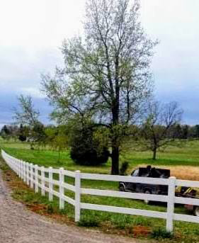A long white vinyl farm fence installed along a dirt road by B&L Fence Co in Youngstown, OH.