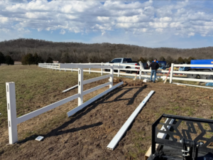 White vinyl farm fence installation in progress with materials and equipment by BK FenceWorks in Wentzville, MO.