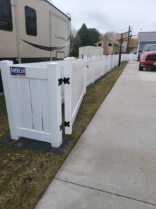 A white vinyl fence installed along a residential driveway next to an RV by American Fence Company of Norfolk in Grand Island, NE.