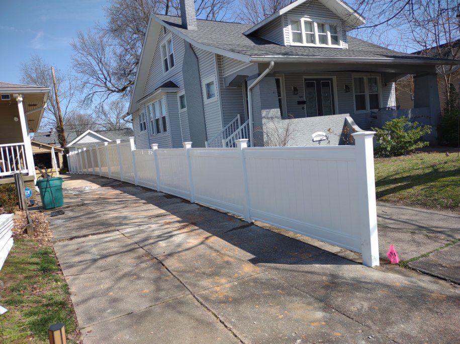 A long white vinyl fence installed along a residential driveway by Nailed It Fencing and Exteriors in Evansville, IN.