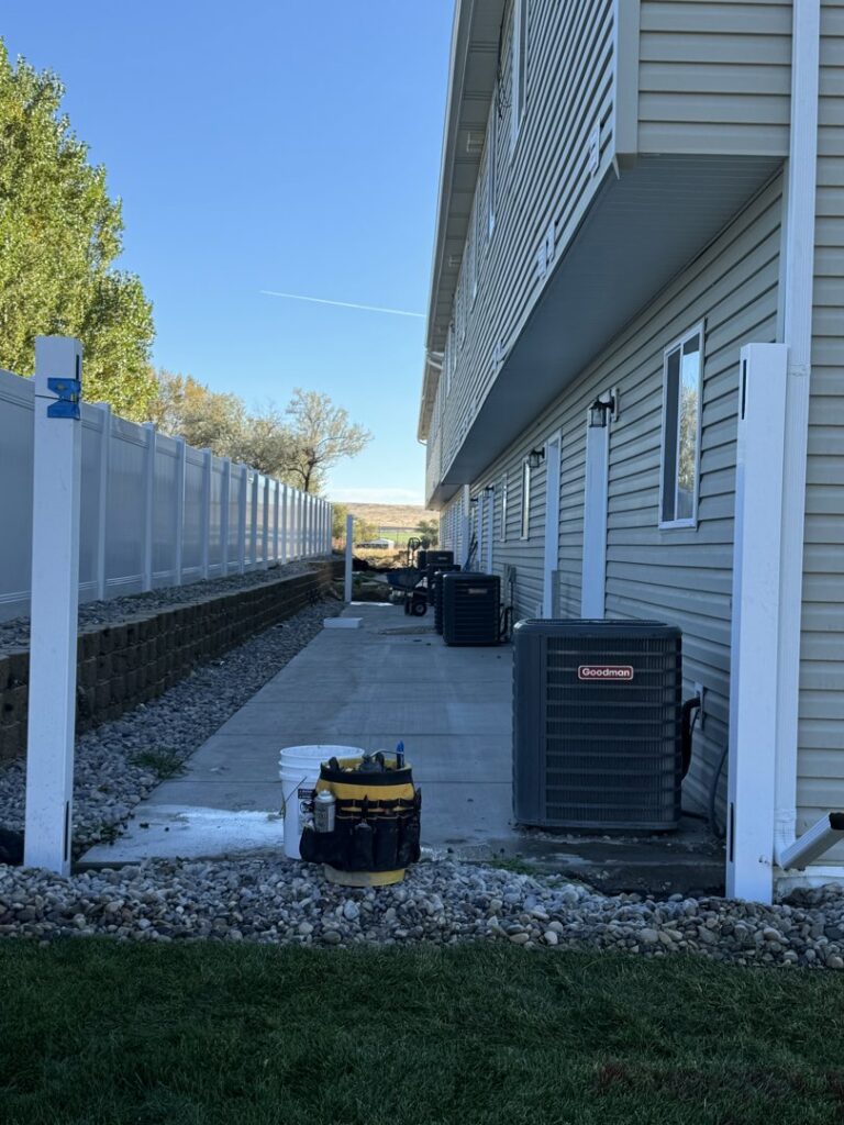 A white vinyl fence installed alongside a commercial or multi-unit building by 208 Fence and Gate in Idaho Falls, ID.