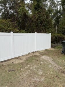 A section of a white vinyl privacy fence installed in a backyard by JBunlimitedfencingllc in Savannah, GA.