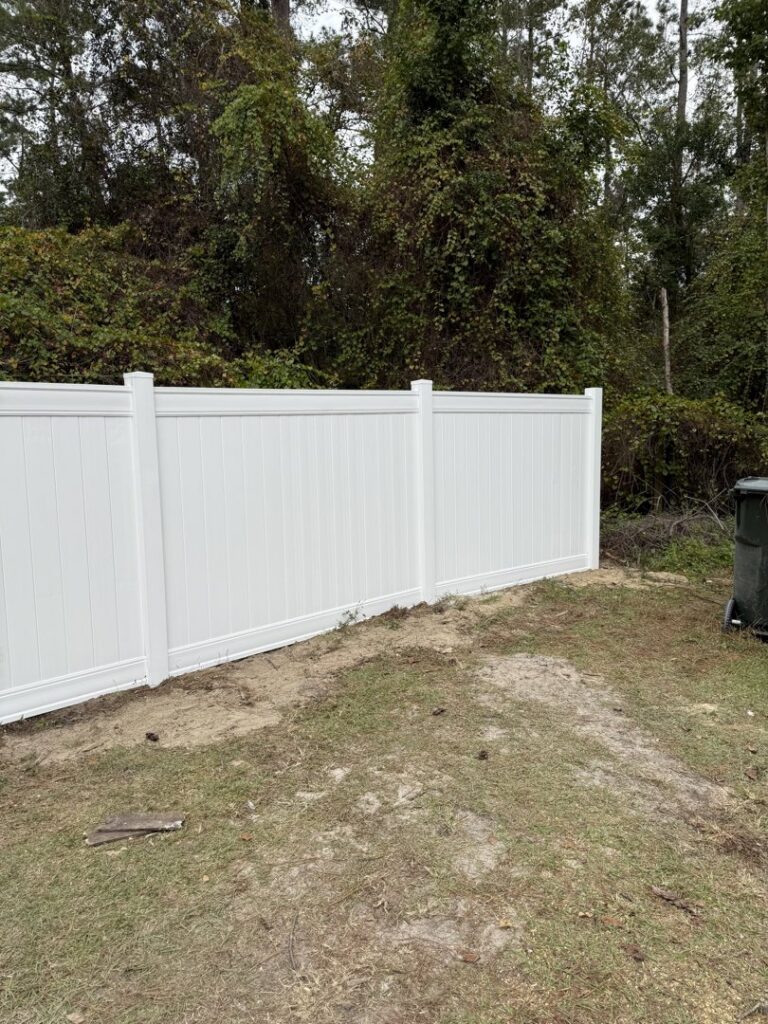 A section of a white vinyl privacy fence installed in a backyard by JBunlimitedfencingllc in Savannah, GA.