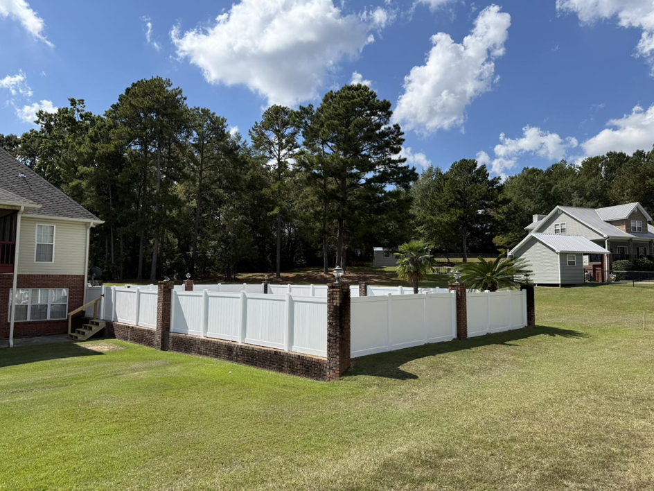 An elegant white vinyl fence with decorative brick pillars installed by Integrity Construction and Fencing, LLC in Clanton, AL.