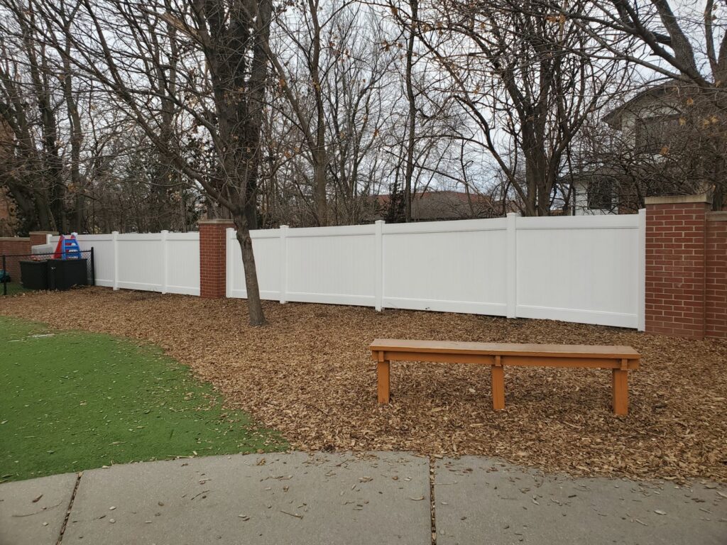 A long white vinyl fence with decorative brick pillars installed by Pride Fence in Peabody, MA.