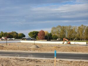 A newly installed long white vinyl fence bordering a construction site by Josey's Fencing LLC in Caldwell, ID.