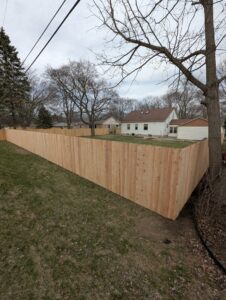 A newly installed white vinyl privacy fence running alongside a driveway by Safe Yard Fence - Waukesha County in Waukesha, WI.