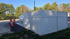 A white vinyl fence enclosure built around a large propane tank by Creative Fence in Casco, ME.