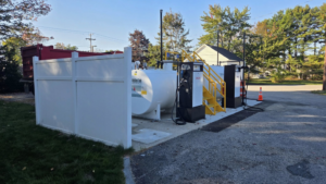 A white vinyl fence enclosure for a commercial fuel tank and pump station by Creative Fence in Casco, ME.