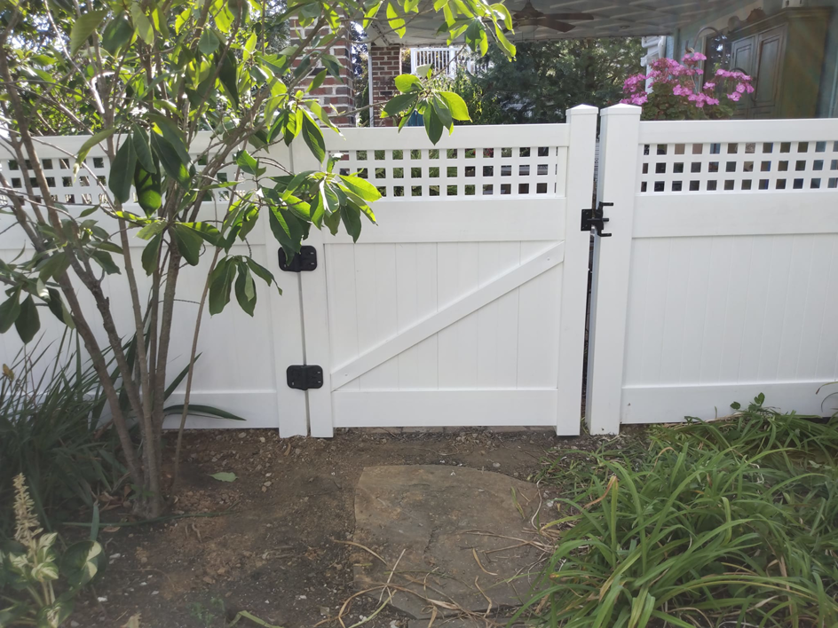 A white vinyl fence gate with black hinges and latch, featuring a lattice top, installed by Low-Level Construction LLC in York, PA.
