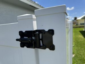 A close-up view of a durable black hinge on a white vinyl fence gate, installed by Inovation Fence in Fort Worth, TX.