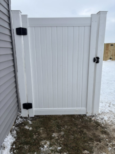 A newly installed white vinyl fence gate next to a residential home by H&M Fencing LLC in Decatur, IN.