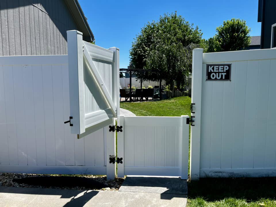 A white vinyl fence with a gate and "KEEP OUT" sign installed by Custom Vinyl Fabrication in Omaha, NE.