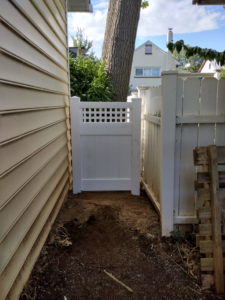 A white vinyl fence gate with a lattice top installed in a narrow side yard by Low-Level Construction LLC in York, PA.