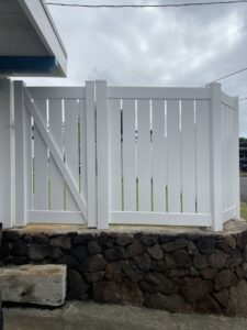 A white vinyl fence with a gate installed on a stone base by Redmond Valleywide - Hawaii's Fence Company in Kapolei, HI