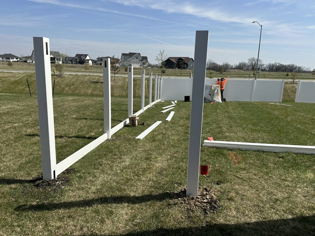White vinyl fence installation in progress, with posts and rails being set by Top Rail Fence Des Moines in West Des Moines, IA.