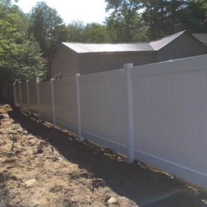 A section of white vinyl fence recently installed with disturbed ground around its base, showcasing work by David Platania Fence in Derry, NH.